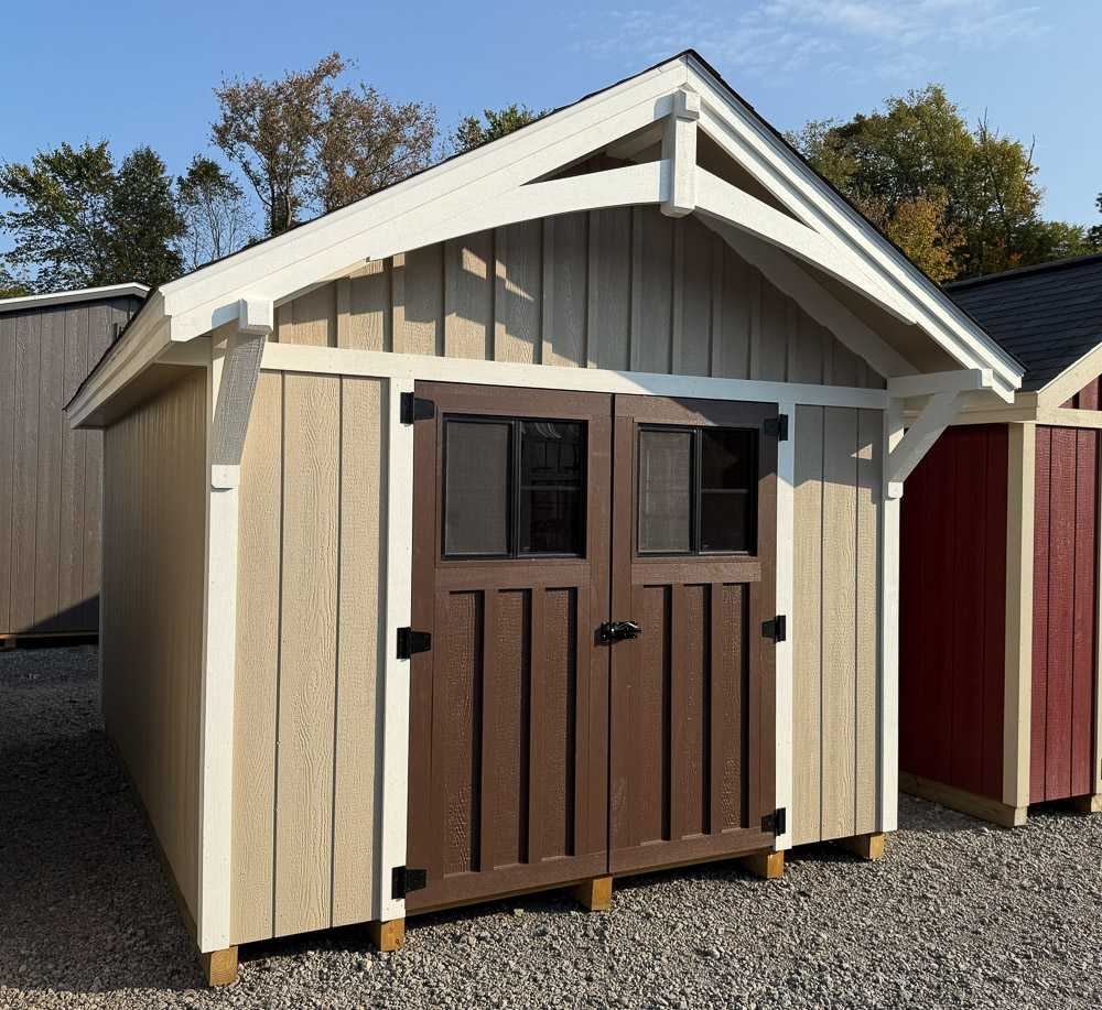 Beige craftsman-style storage shed from Salem Structures with brown double doors, board-and-batten siding, and decorative white trim.